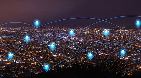 A nighttime aerial view of a city with blue location pin icons marking various points