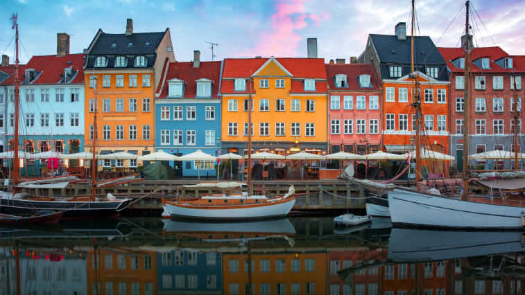 Boats anchored in a canal in front of colorful buildings in Copenhagen