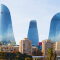 The blue, reflective Flame Towers in Baku, Azerbaijan towering over other buildings and trees