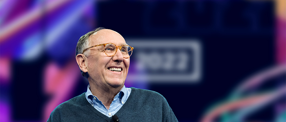 Jack Dangermond smiling on stage at Esri User Conference overlaid with a play button that opens the video in a pop-up module when clicked