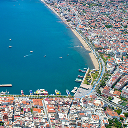 Aerial view of a bustling seaside town with blue ocean waters dotted with yachts