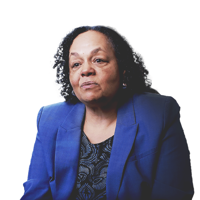Darlene Flynn, direttrice esecutiva di Oakland per le questioni razziali e la parità, con un blazer blu, seduta davanti a un paesaggio urbano.