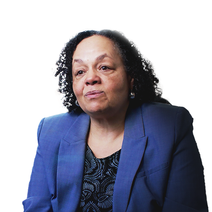 Portrait of Darlene Flynn mid-speech wearing a blue suit with a modern city in the background brightly lit for dusk