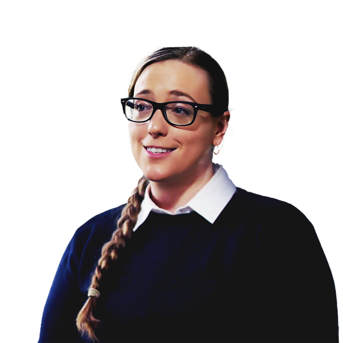 Molly Burhans smiling in a dark blue sweater with a background of gold and orange desert mountains beneath a windswept blue sky