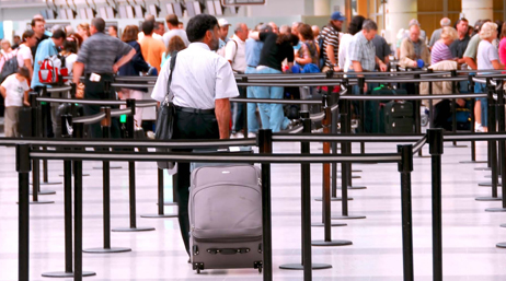 Man with a suitcase joining a line in an airport
