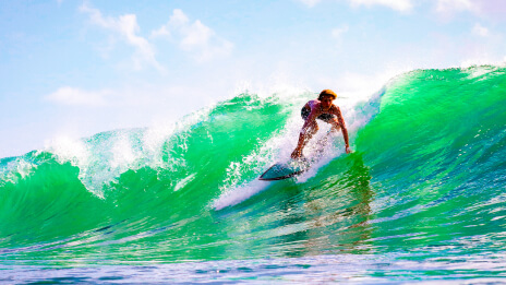 A surfer in action on a large green-blue wave under a sunny sky  
