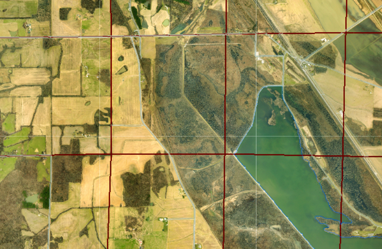 An aerial view of a large rural area overlaid with a red grid