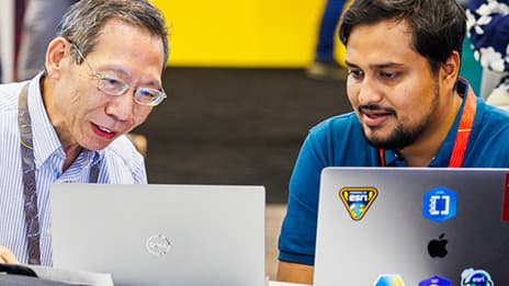 Esri expert and event attendee each with an open laptop smiling and talking