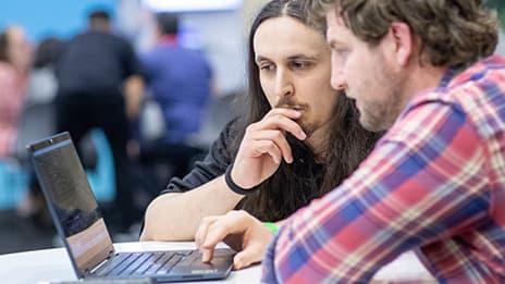 Two people intently focused on an open laptop in the event Expo
