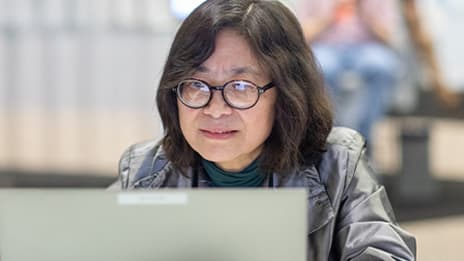 Event attendee with short dark hair wearing glasses working on a computer