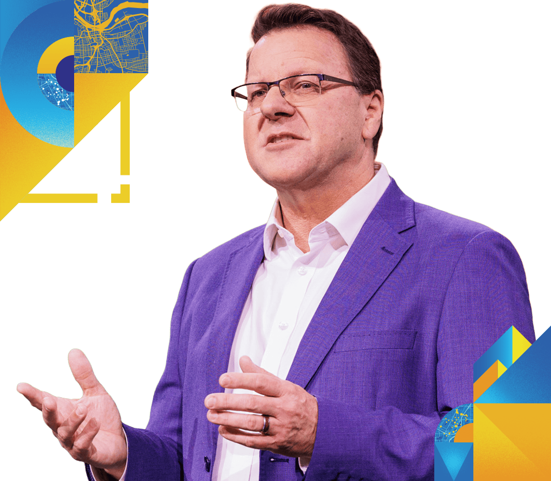 Presenter in a purple jacket speaking onstage