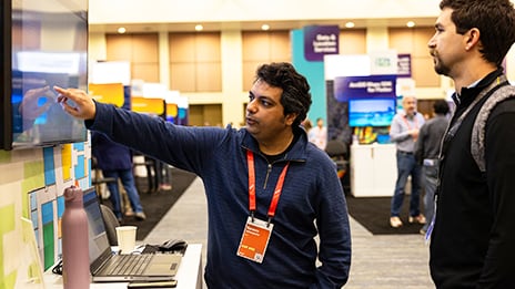 Two people reviewing content on a vertical display as one holds a marker and gestures
