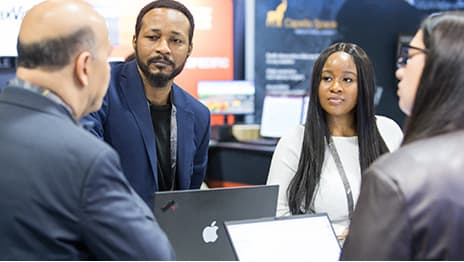 Group of Expo attendees listening to an exhibitor explain a product