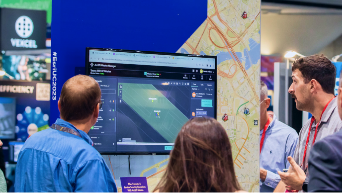 Small group of trade show attendees watching a demonstration on a display monitor