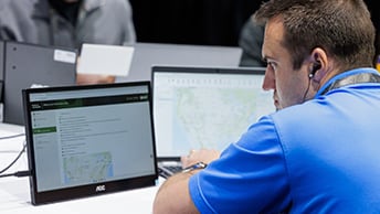 Conference attendee studies information on a laptop screen and compares it with an external display to one side
