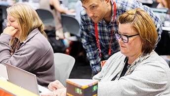 Conference attendee working at a laptop, with an Esri staff member looking on