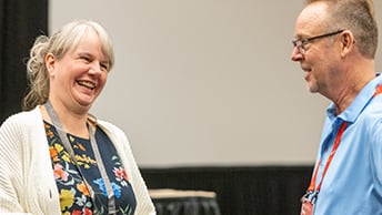 Two attendees in the Expo area smiling at each other