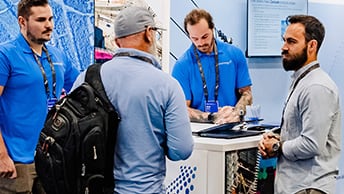 Esri experts listening to a conference attendee at a booth in the Esri Showcase