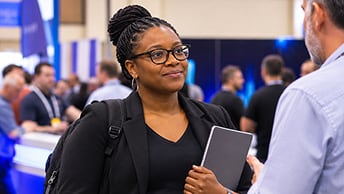 Conference attendee studies information on a laptop screen and compares it with an external display to one side