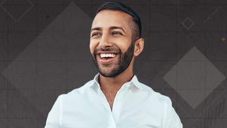 Head and shoulders view of a smiling person with a beard wearing a white button-up shirt looking off to the left