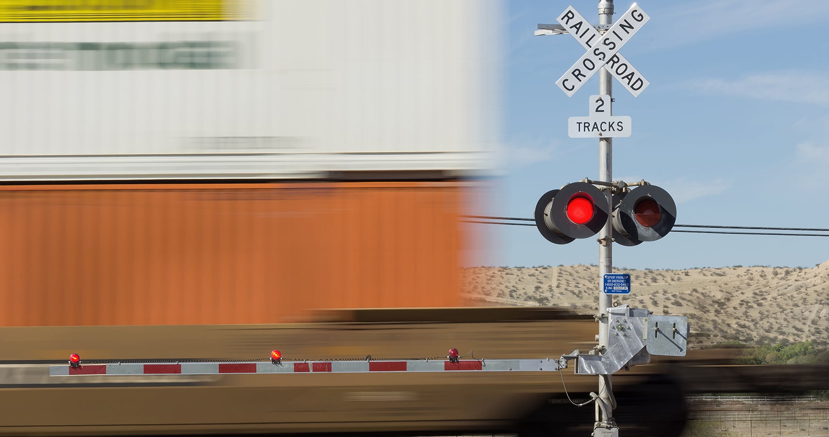 Rail crossing sign indicating two tracks with blurred building in background