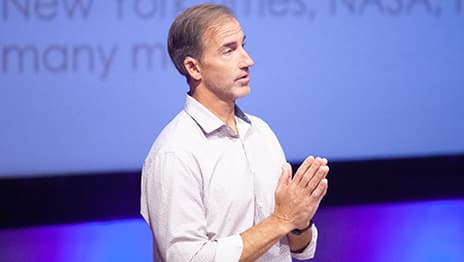 Forum presenter on stage wearing a light-colored button up shirt