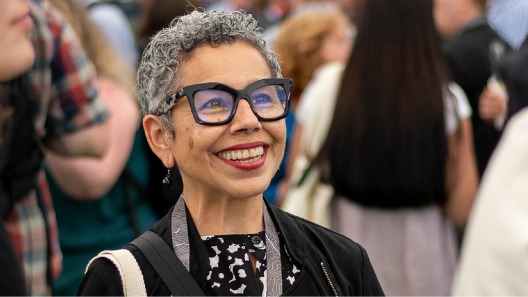 Closeup of a smiling attendee wearing thick framed glasses during a lively networking event
