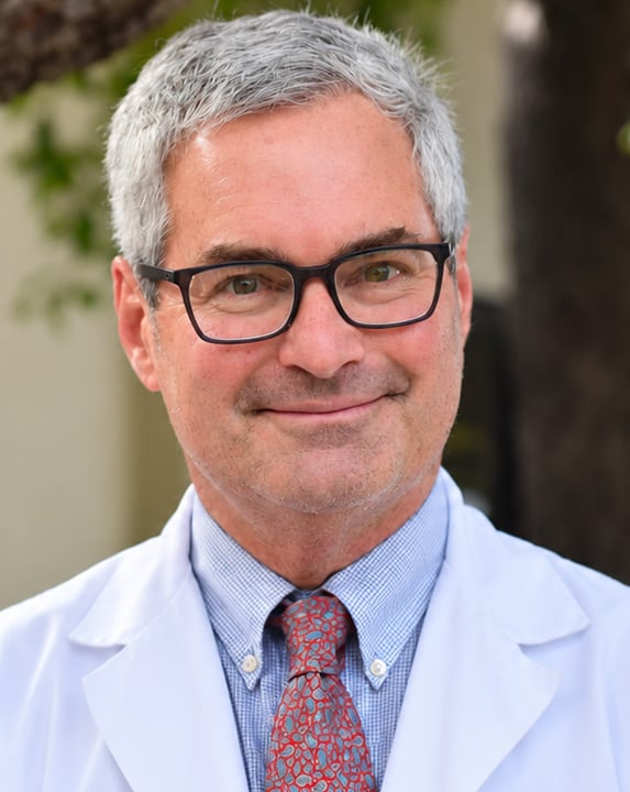 Portrait of Dr. Philip Ente in black rimmed glasses, a blue button-up shirt, and a red patterned tie