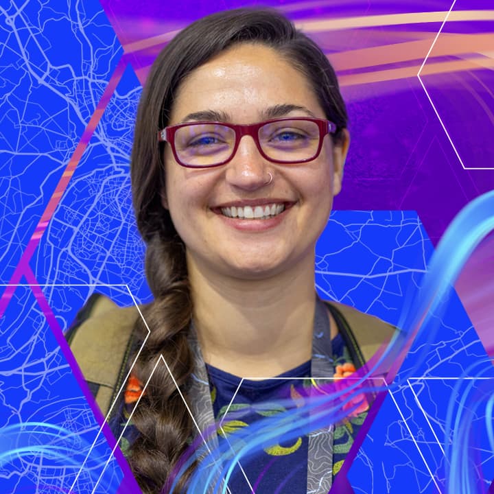 ·	Smiling woman with long dark hair wearing burgundy-framed glasses against a background of multicolored swirls and map elements