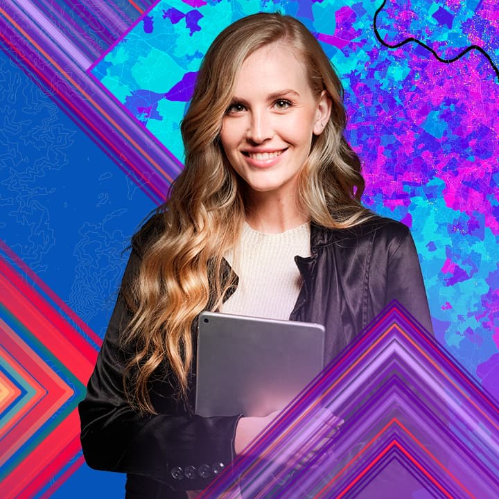 Smiling person with long wavy blond hair wearing a dark jacket and holding a laptop against a background of vibrantly colored map graphics