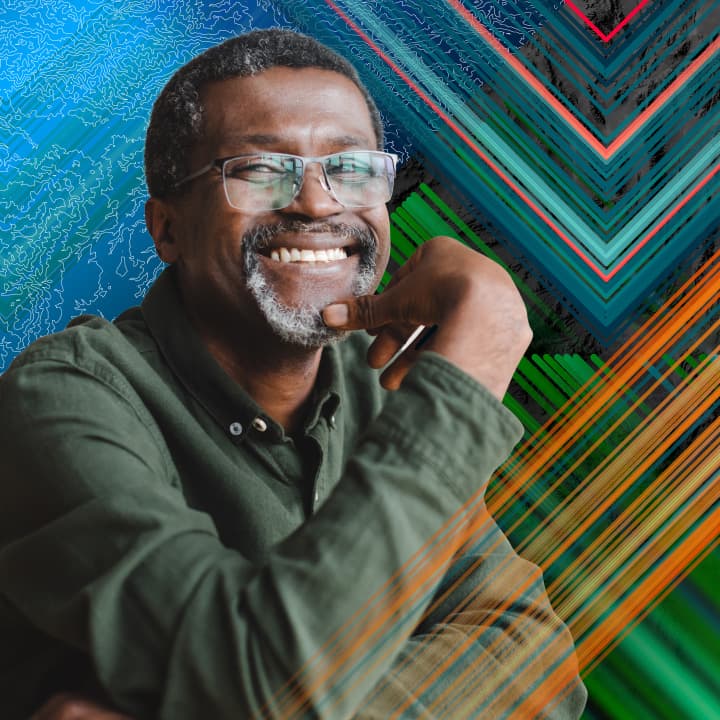 Smiling person with a goatee wearing a hunter green dress shirt and glasses with a multicolor background of interwoven diagonal lines and maps