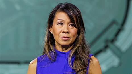 Presenter with long dark hair, wearing a bright blue top, onstage at Esri UC