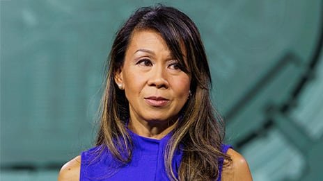 Person in a sleeveless purple top shown from the shoulders up against a softly blurred background