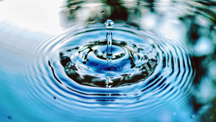 A drop of water causing ripples in a larger pool of water