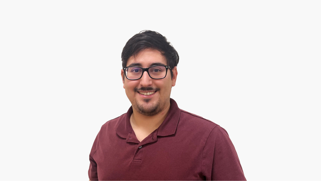 Paul Delagarza smiling, wearing glasses and a t-shirt, in front of a white background