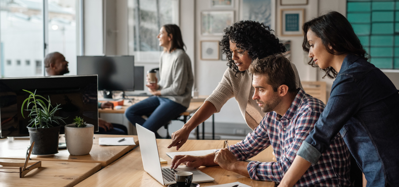 Three coworkers looking at data on a laptop and collaborating on a project 