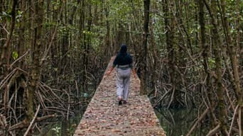 Photo of a woman walking through a dark and beautiful forest