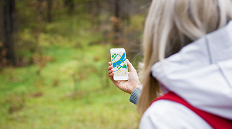 A citizen scientist using a GIS app on their smartphone to collect data in a forest