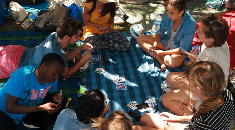 Photograph of young students gathered in a circle playing card games