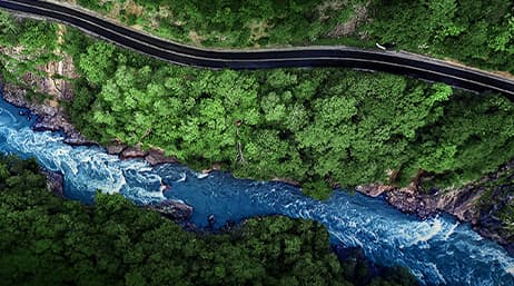An aerial view of a forested area with a highway running parallel to a river
