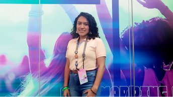 Diana Beltrán standing in front of a blue and purple wall mural at the Esri User Conference