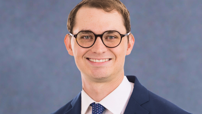 David German wearing glasses and business attire while smiling