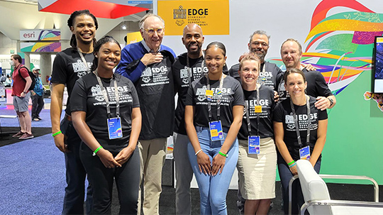 Um grupo diversificado de pessoas vestindo camisetas EDGE combinando na Esri User Conference