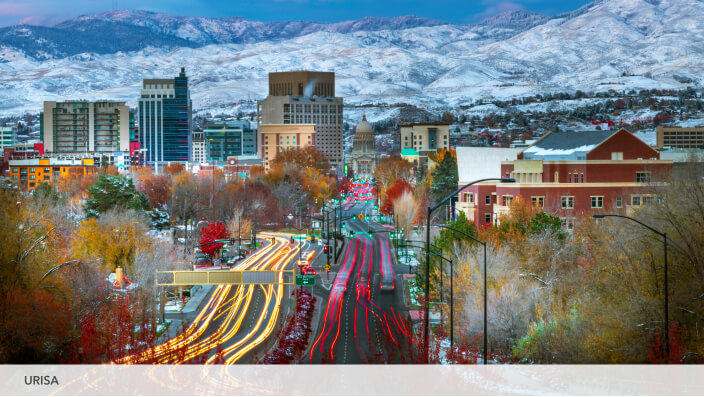 A city with a freeway leading into it and snowy mountains in the background