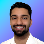Portrait of Haseeb Malik smiling in a white collared shirt with a blue background