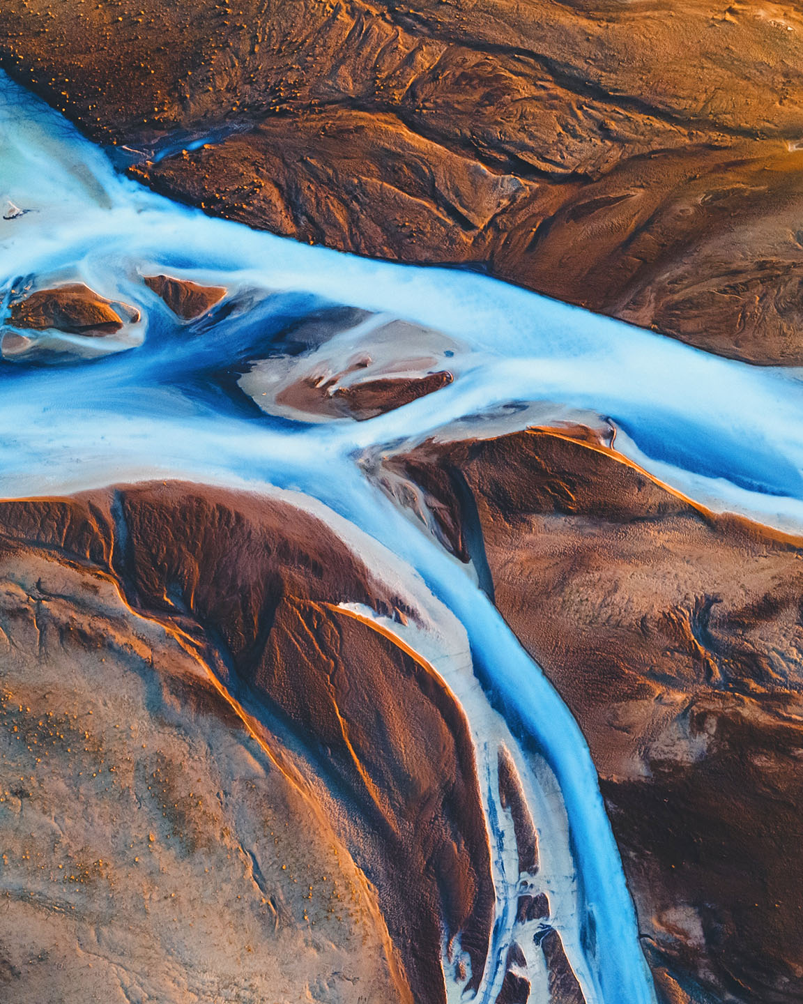 A river flows through a flat, snowy tundra landscape with a plateau rising in the distance