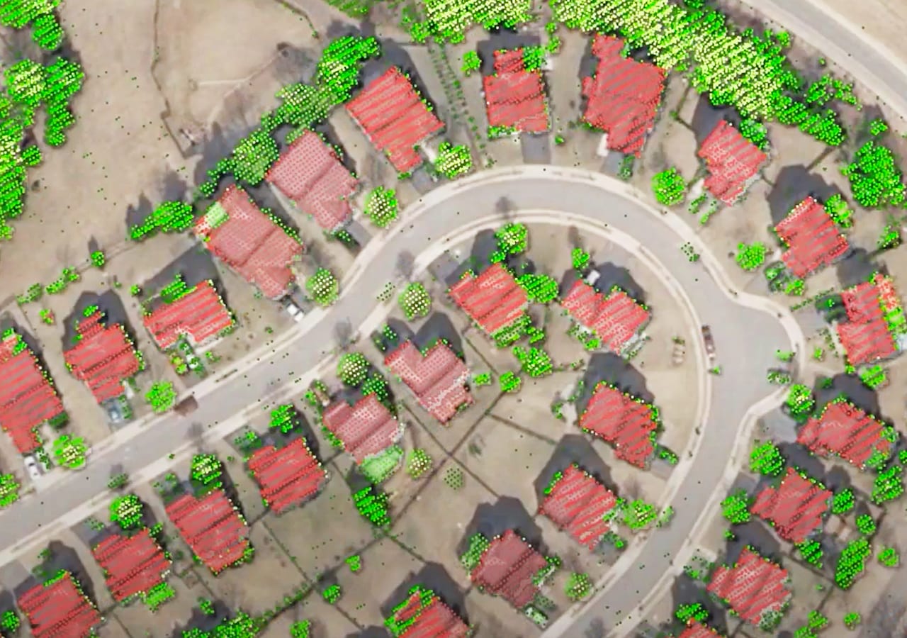 An aerial image of a residential neighborhood shows structures highlighted in red and trees in green