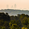 Skyline view of the city of Atlanta with tall buildings, green trees, and light morning fog