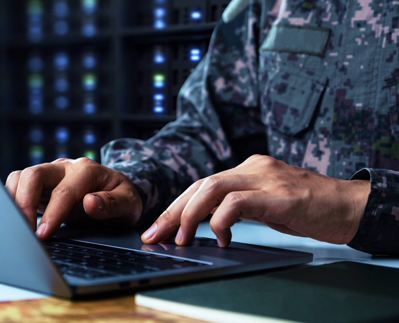 Close-up of military personnel in uniform working on a laptop computer