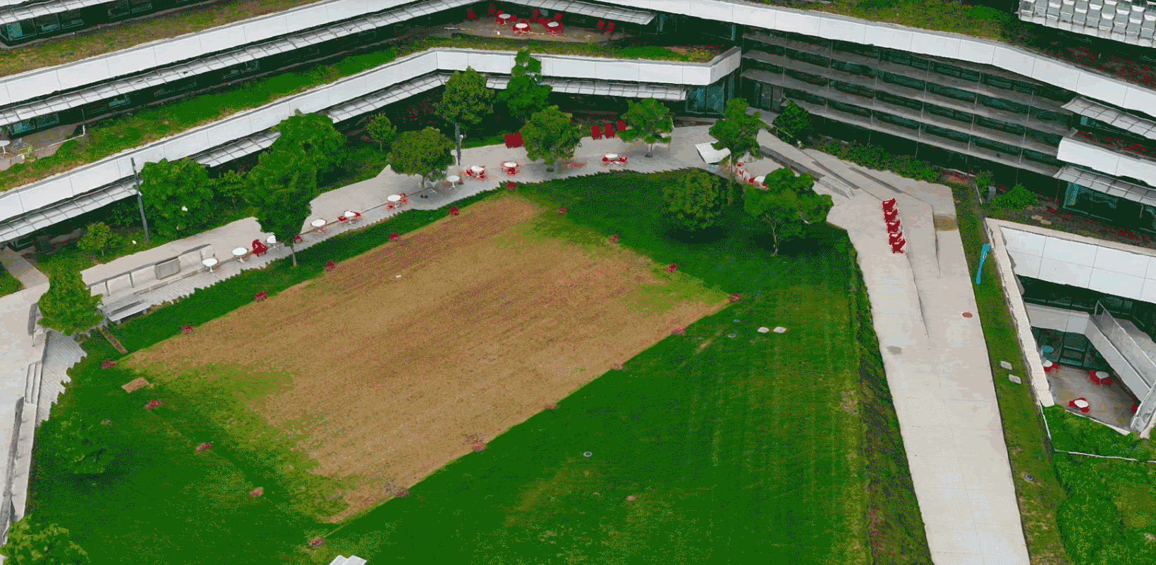 An immersive GIF showcasing 3D reality capture of a large commercial building and the surrounding green grass and roads 